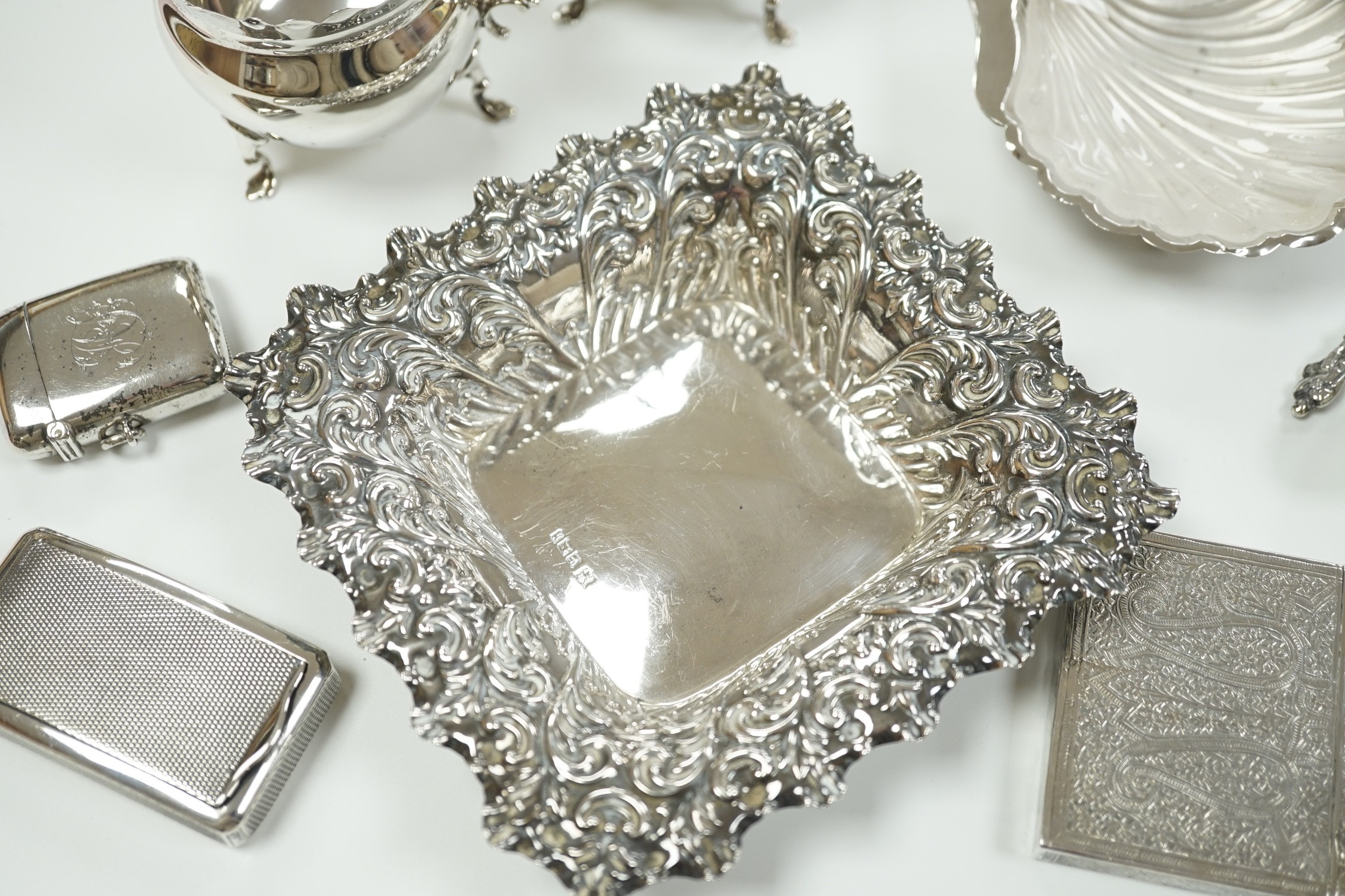 A small group of collectable silver including a repousse bonbon dish, 13.5cm, cigarette case, silver cream jug and sugar bowl, butter shell, vesta case, match sleeve, two apostle teaspoons and a George III curved silver